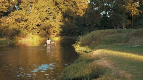 Man Riding a Wooden Boat on the River