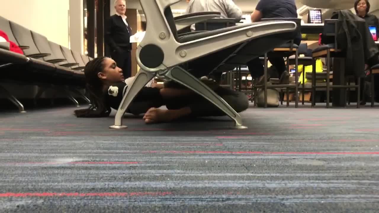 Young Woman At An Airport Limbos Under A Chair