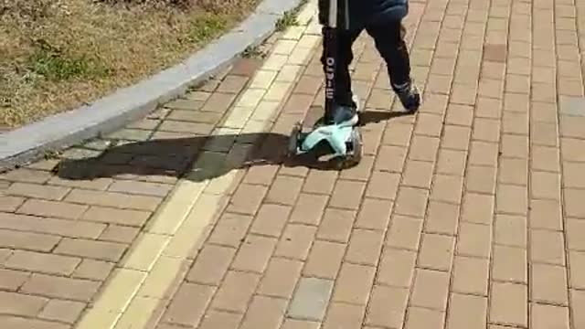 This is a video of a baby riding a kickboard happily.