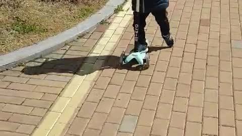 This is a video of a baby riding a kickboard happily.