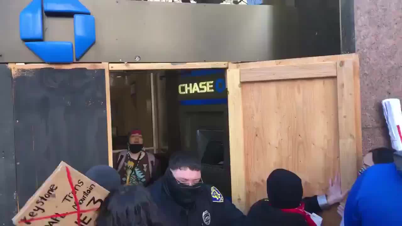 Guard tries to hold back protesters in Portland who are harassing him in Chase Bank.