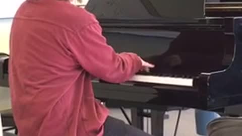 Glasses red shirt plays microsoft theme on the piano