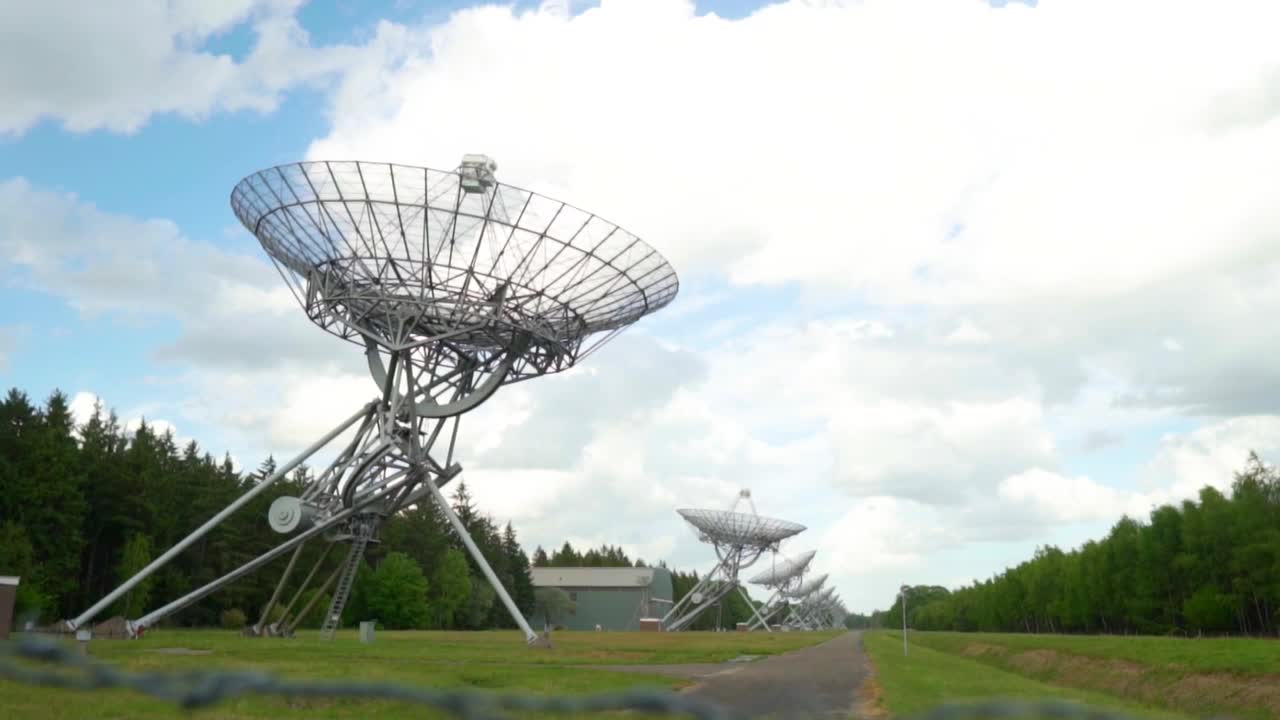 Large satellite dishes lined up in a meadow