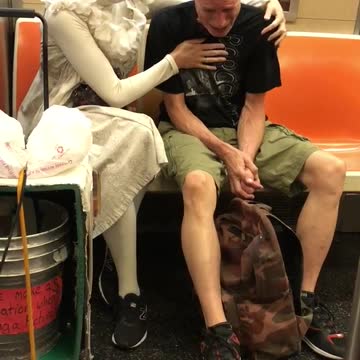 Woman in white comforts crying man on train