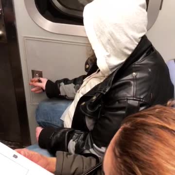 Man in black jacket and white sweater smokes in subway