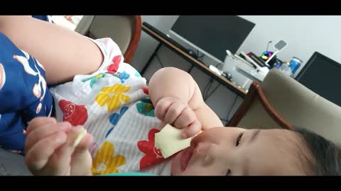 baby eating cheese while lying down