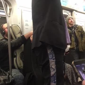 Woman looks up from book to see couple talking on subway
