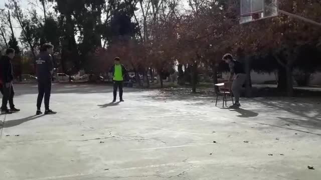 Guys jumping off chair to rebound basketball off of backboard second guy falls and chair falls over