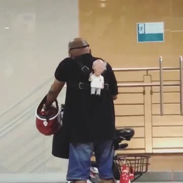 Man with old man stuffed toy on his back