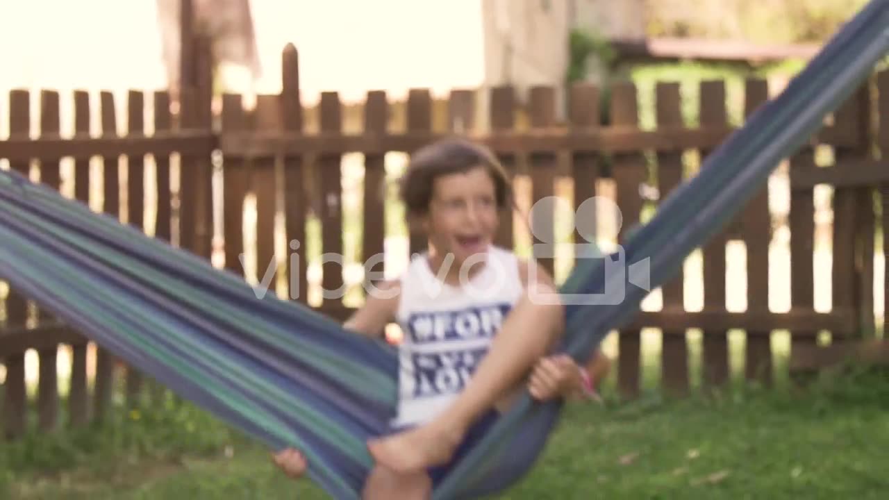 Young happy little girls in summer camp lying in colorful hammocks