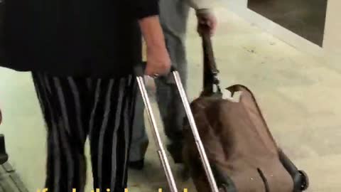 An older man dragging brown suit case