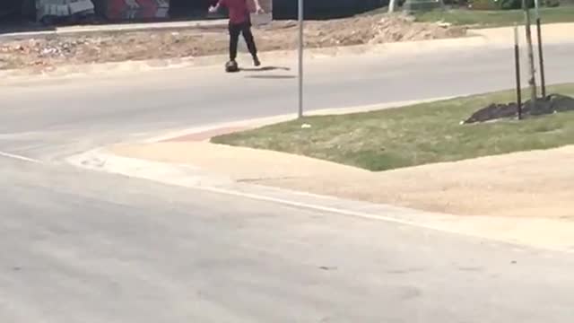 Red shirt skater falls on butt in front of stop sign