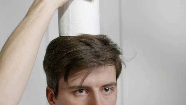 A Man Balancing Toilets Papers On His Head
