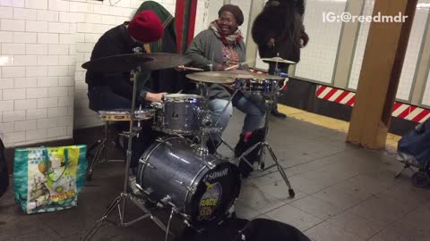 Man and woman play drums on subway platform