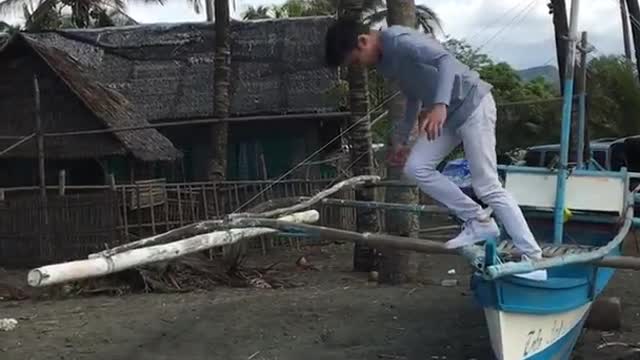 Boy does a flip off canoe on land, falls