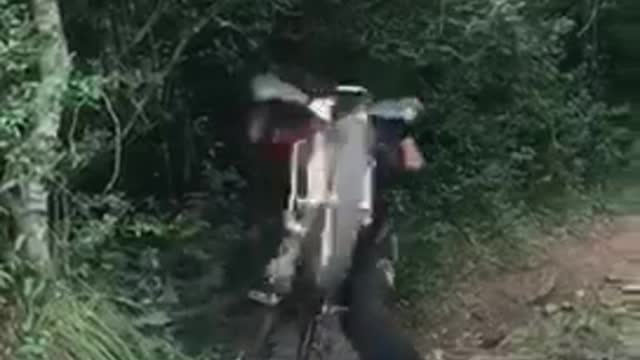 Dirt biker rides on dirt trail and flips over his bike