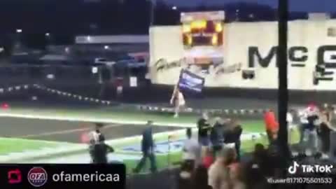 Man w/ Trump Flag runs across HS sports field to raucous applause & cheers.