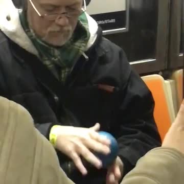 Old man plays with anti gravity ball on subway train