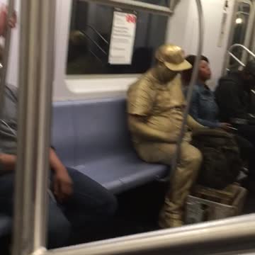 Man covered in all gold paint on train