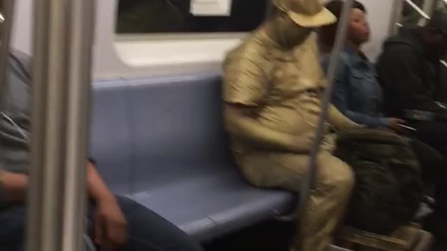 Man covered in all gold paint on train