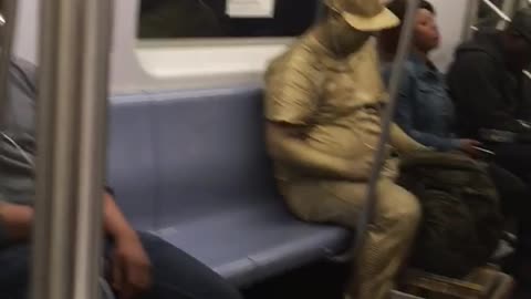 Man covered in all gold paint on train
