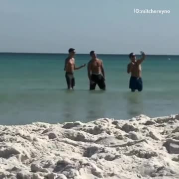 Three shirtless dudes trying to take selfie in water beach