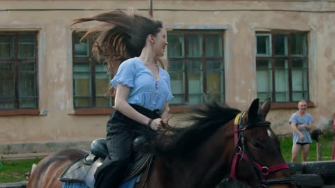 Young smiling happy woman with long hair riding a horse