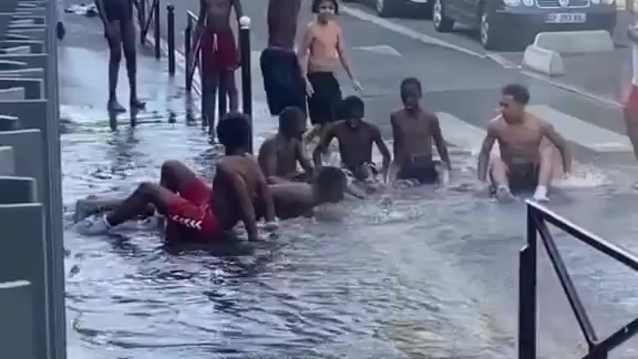 African migrants burst a fire hydrant to cool off for a while in a Paris.