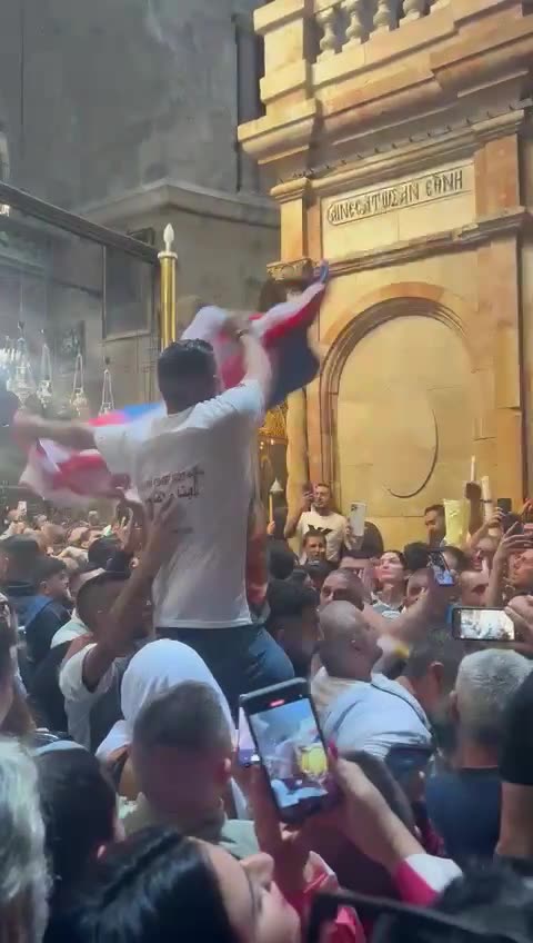 A Palestinian man carries a Russian flag during the Holy Fire ceremony inside the Church