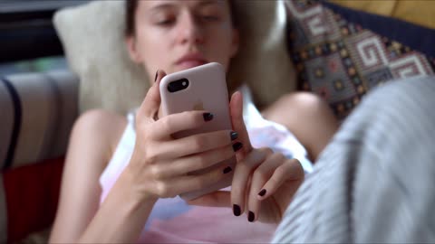 Young girl on the couch playing with the phone