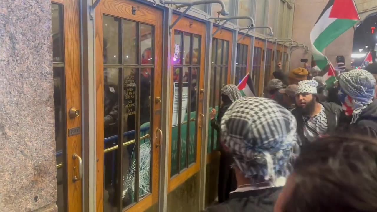 protesters enthusiastically knock on the doors of Grand Central Station in NYC