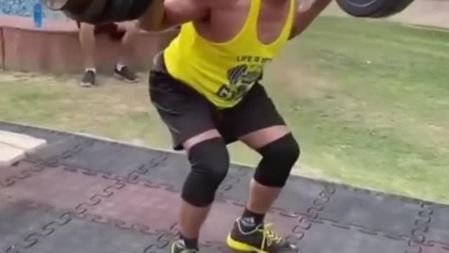Elderly Fitness Coach Does Squats While Lifting Heavy Barbell