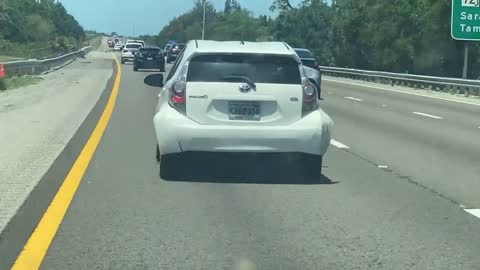 Person Driving Down the Highway While Their Bumper Hangs on for Dear Life