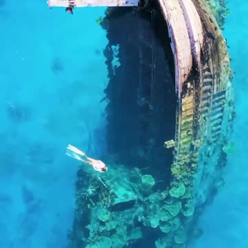 In the clear waters surrounding Keioda, Maldives, lies a sunken ship half submerged.