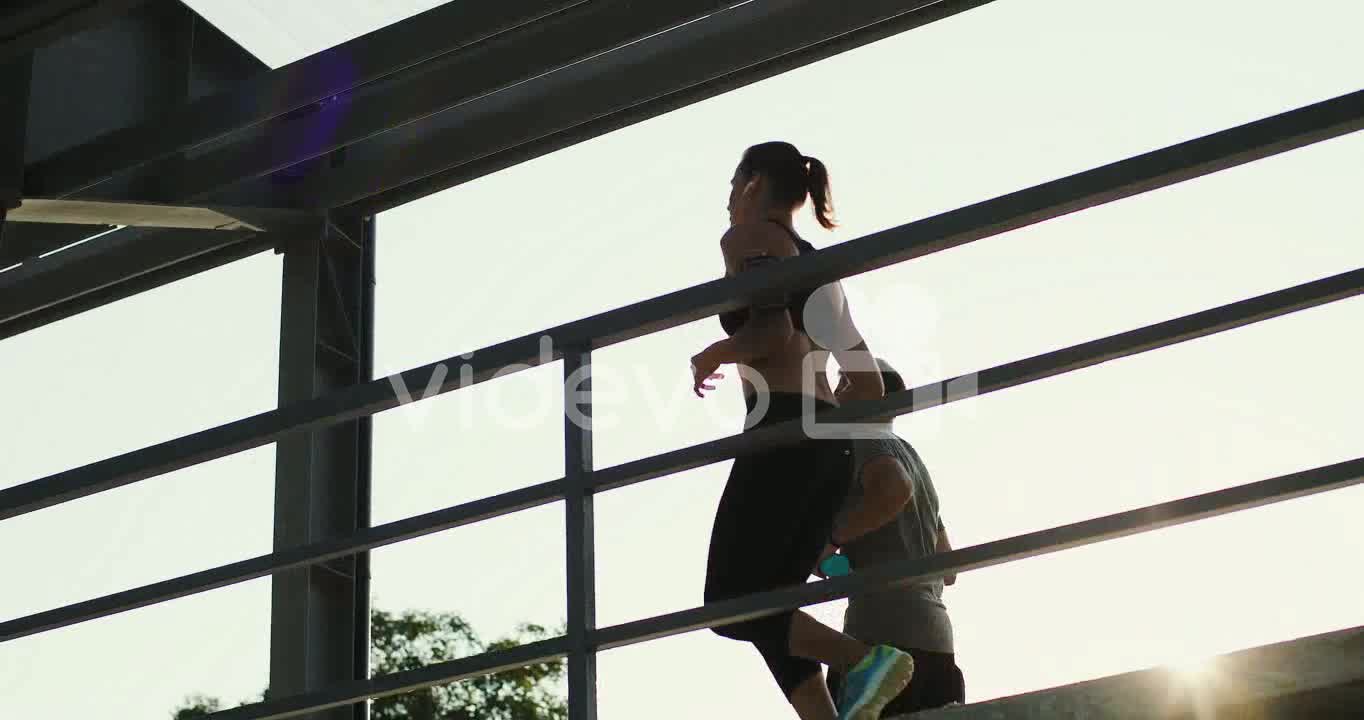 Young Couple Of Joggers Running At The Stadium Passage While Doing Sport In The Morning