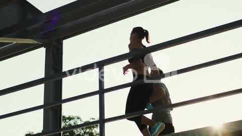 Young Couple Of Joggers Running At The Stadium Passage While Doing Sport In The Morning