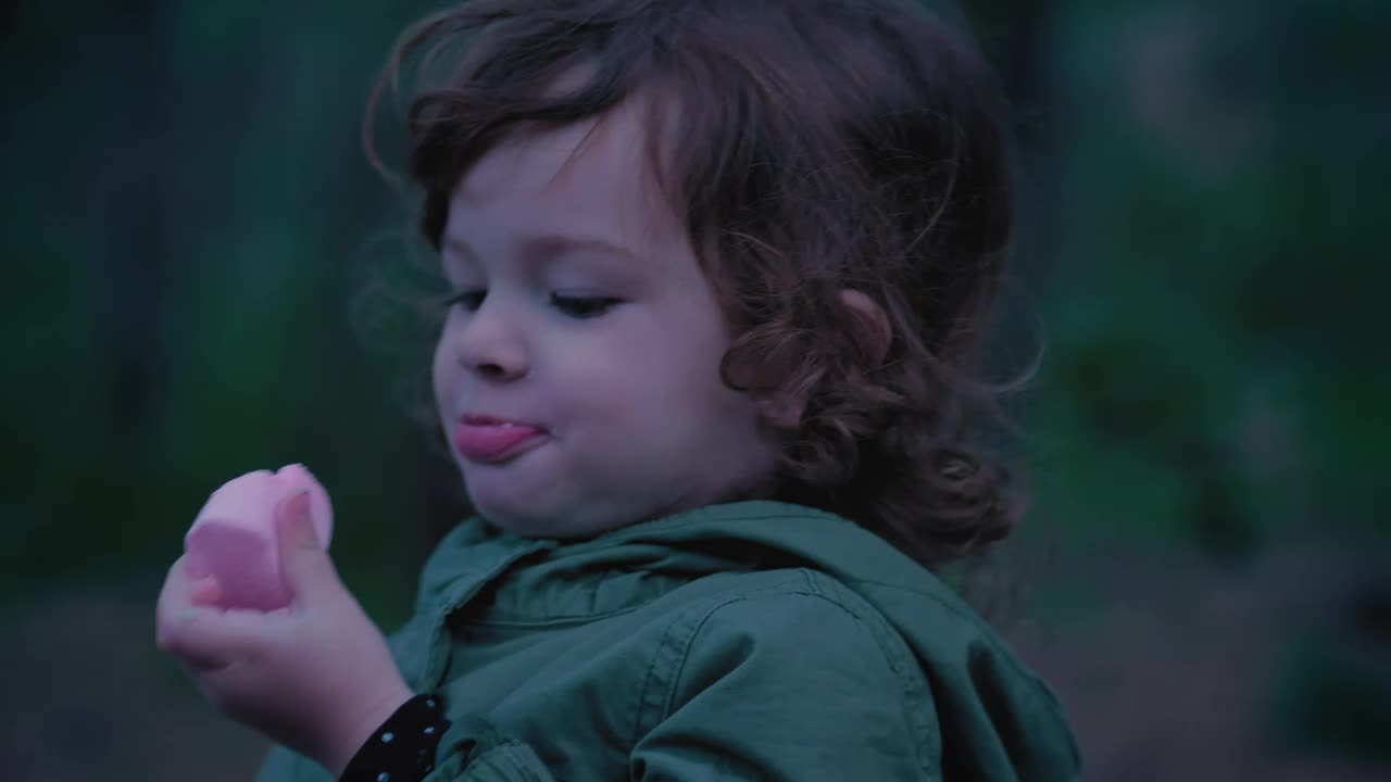 Little girl in nature eating a marshmallow