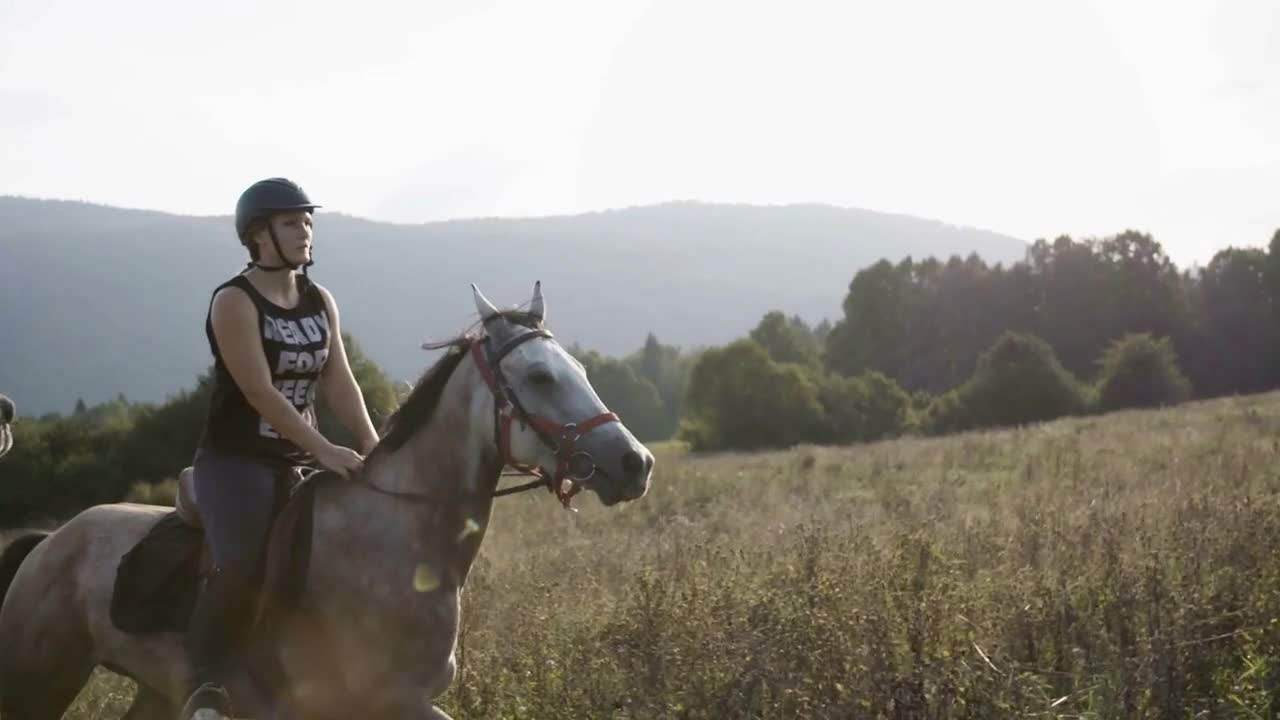 Woman is riding a horse on meadow