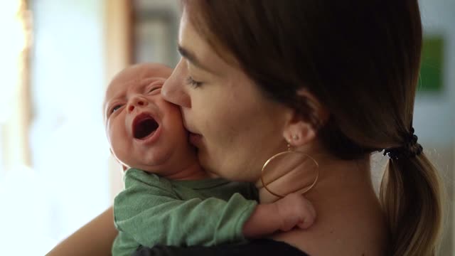 Mom kiss her little baby in her hands bed