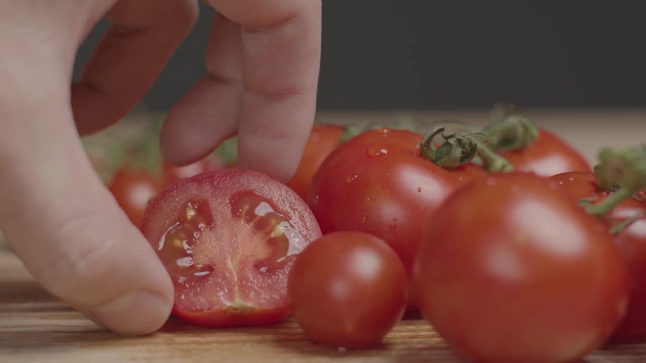 Close Up Shot of Hand Placing Half a Tomato Next to Vine of Tomatoes-A close-up shot of a hand placi