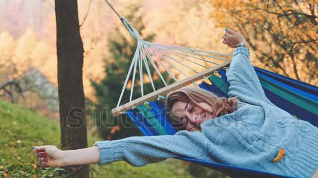 Wakes Up after Sleep in a Hammock in Autumn.