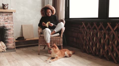 Woman Caressing A Dog While Reads A Book