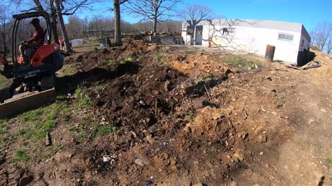 Grading the front yard with the mini-excavator and hauling the tractor.