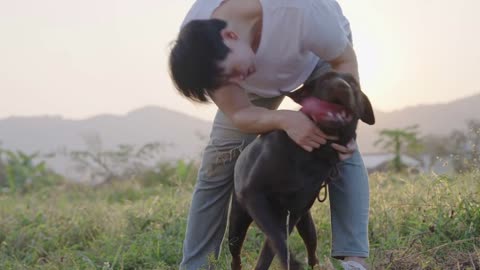 Asian playful male owner walking from behind and stroking on his energetic dog