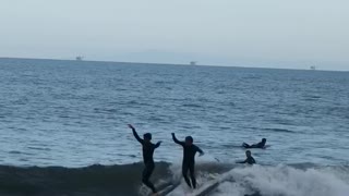 Two guys surfboarding smaller guy runs into other guy and falls into water