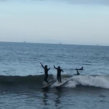 Two guys surfboarding smaller guy runs into other guy and falls into water