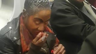 Woman applying red lipstick with her finger on subway train