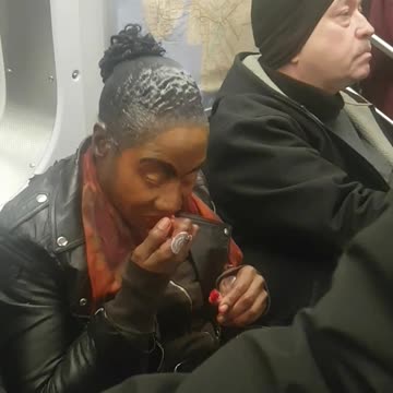 Woman applying red lipstick with her finger on subway train