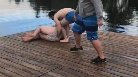 Two guys try to push friend off dock but he falls down