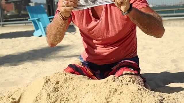 Lucky man finds dollars while digging sand on the beach, sneaks it into his pocket